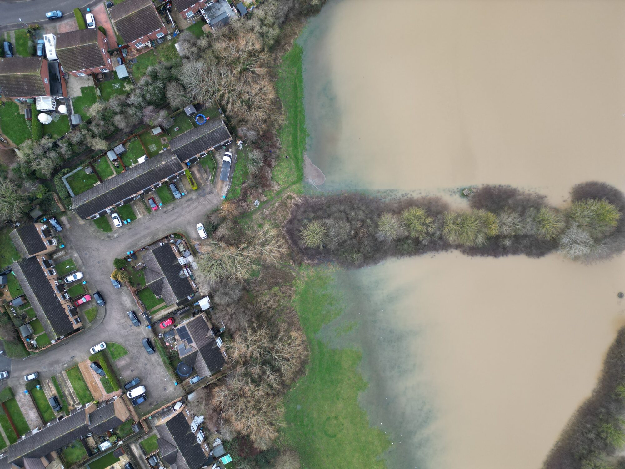 Drone imagery of flood waters. Overhead view of a housing estate in north Aylesbury. Flood waters in floodplain next to a houses. By skyeyeimagery.com
