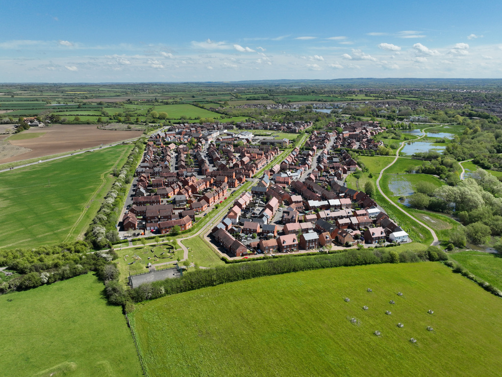 UAV Drone imagery of a housing estate in Buckinghamshire. Surrounded by green fields and neatly laid out houses.